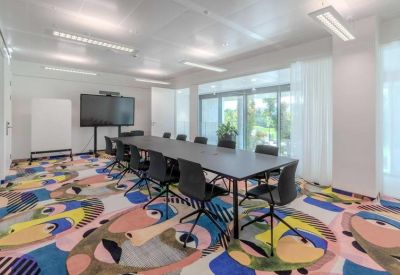 Large conference room with a long table and artistic face-patterned carpet.