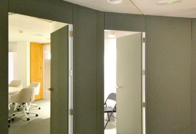 Modern hallway with olive green walls leading to several private office suites.