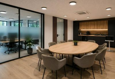 Communal meeting area featuring a large oval wooden table and an integrated kitchenette.