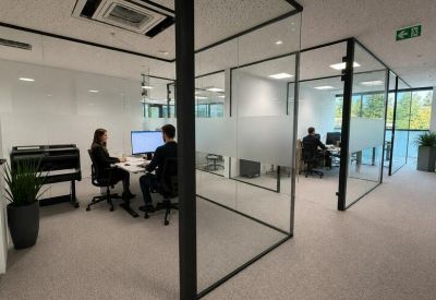 Modern glass-partitioned office space with workstations and a privacy film.