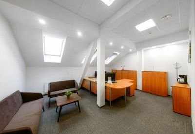 Bright office suite with wood-toned desks and comfortable brown sofas.