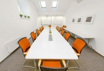 Symmetrical meeting room with a long white table and bright orange chairs.