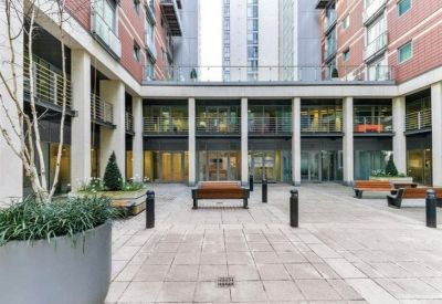 Spacious internal courtyard with stone paving, wooden benches, and large planters.