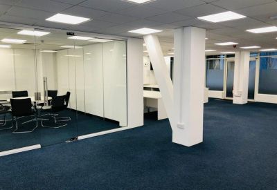 Open-plan office space showing glass partitions and a central structural column.