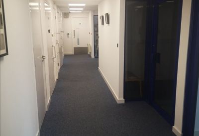 Modern office corridor with blue-framed glass doors and white walls.