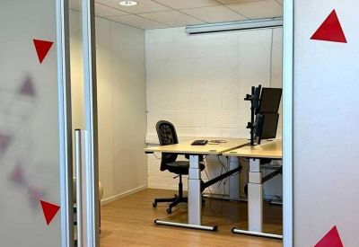 Bright workspace featuring height-adjustable desks and a ceiling-mounted projector.