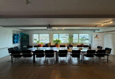 Large formal boardroom with a long dark table and rows of black chairs.