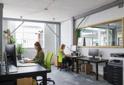 Spacious open-plan office with grey industrial beams and large wooden-framed mirrors.