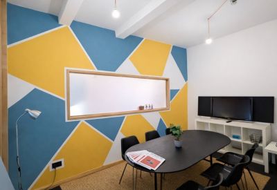 Modern meeting room featuring a vibrant yellow and blue geometric accent wall.
