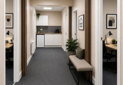 Hallway leading to a shared kitchen area with white cabinetry and a small seating bench.