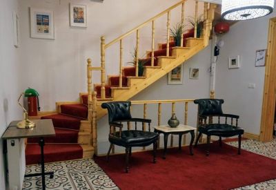 Wooden staircase with a red runner carpet and a small lounge seating area.