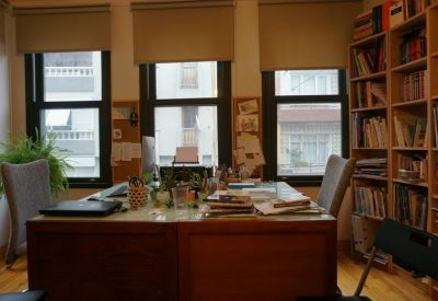 Large wooden shared desk in a sunlit room with built-in bookshelves.