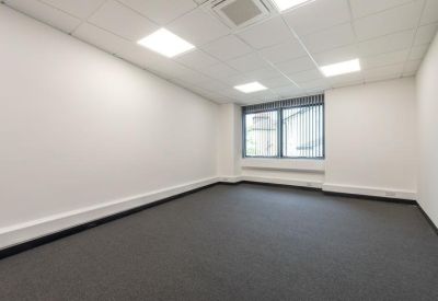 Bright, empty open-plan office suite with grey carpeting and large windows.