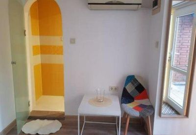 Office corner showing a yellow arched doorway and a patchwork chair by a small white table.