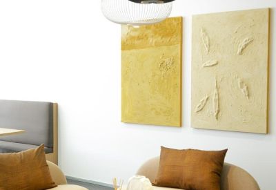 Modern break area with curved beige sofas, a low coffee table, and artistic wall hangings.