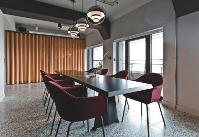 Sleek meeting room featuring a long dark wood table, velvet chairs, and pendant lighting.