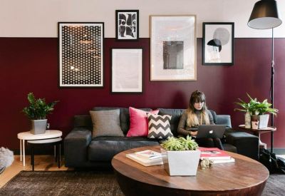 Cosy lounge area with a burgundy feature wall, gallery art, and a plush leather sofa.