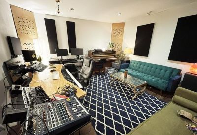 Spacious creative studio with music mixing equipment, teal sofa, and patterned rug.