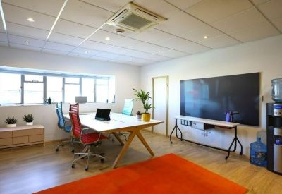 Professional meeting room with a large screen, white table, and vibrant orange rug.