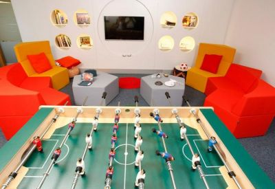 Game room featuring a foosball table and comfortable red and yellow lounge chairs.