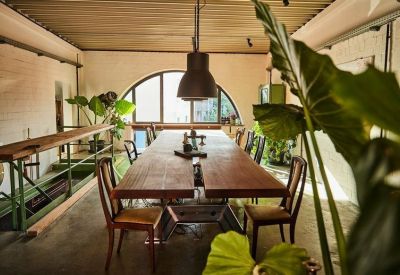 View of a rustic meeting table with mismatched chairs and green leafy plants.