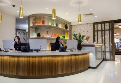 Curved wooden reception desk with bright pendant lights and decorative glass vases.
