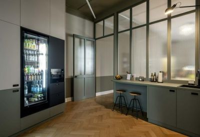 Modern communal kitchen area with a beverage fridge, breakfast bar, and glass partitions.