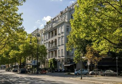Exterior view of the ornate historical building facade at 96, Kurfürstendamm with lush green trees.