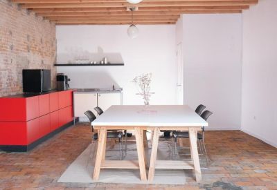Kitchen and dining area with red cabinetry and a large wooden trestle meeting table.