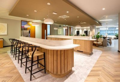 Sleek wooden coffee bar with a marble countertop and high-backed black chairs.