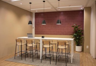 High-top collaboration table with tall wooden stools against a textured red wall.