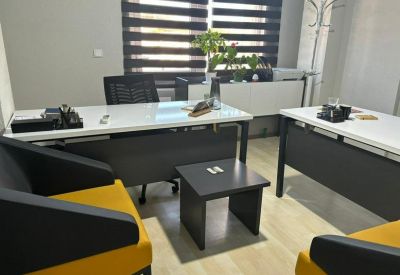 Modern office space with white desks and vibrant yellow and black visitor chairs.