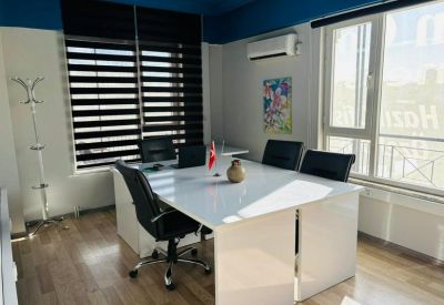 Professional conference area with a sleek white table, black executive chairs, and natural light.