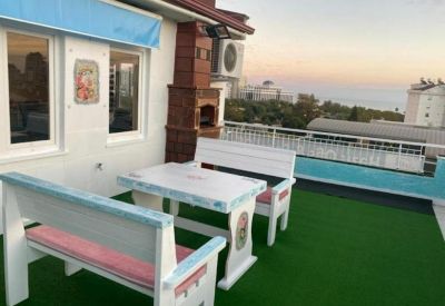 Rooftop terrace featuring white picnic-style seating on green turf with coastal views.