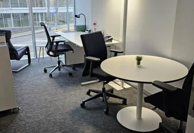 Bright private office featuring a round meeting table and professional workstations.