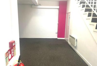 Empty office area featuring a bright pink accent pillar and dark carpeting.