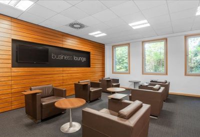 Business lounge with wood-paneled walls, leather armchairs, and coffee tables.