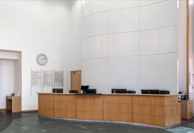 Professional reception area with a long wooden desk and high white ceiling.