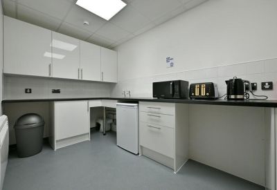 Modern communal kitchen area with white cabinetry and integrated appliances.