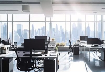 Bright open-plan workspace with multiple computer desks and floor-to-ceiling city views.