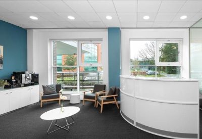 Bright reception lobby featuring a curved white desk and lounge seating.