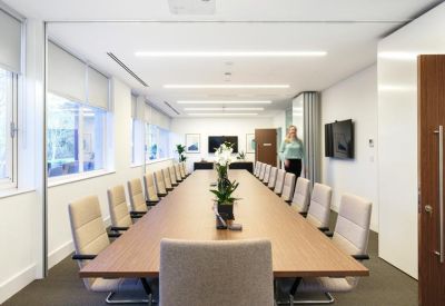 Large boardroom with a long wooden table, plush cream chairs, and expansive windows.