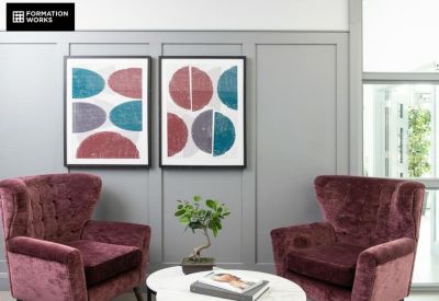 Lounge area featuring two plum-colored armchairs and abstract wall art.