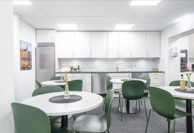 Bright kitchen and dining area with modern white cabinetry and forest green chairs.