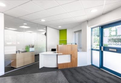 Modern reception lobby with a curved white and wood desk and glass partitions.