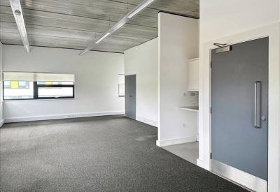Empty open-plan office space with grey carpeting and white walls.