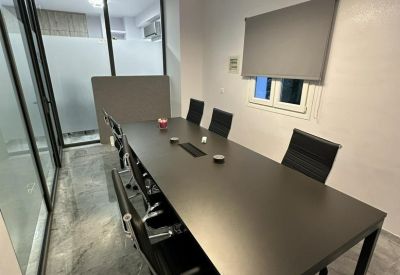 Professional meeting room with a dark long table, black chairs, and a geometric pendant light.