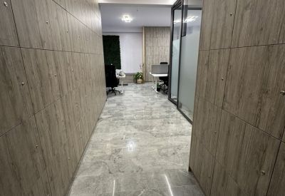 Wood-paneled corridor leading to a bright workspace with marble flooring and integrated LED lighting.