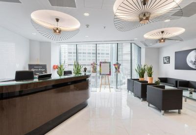 Modern reception area with a dark wood desk, stylish disc pendant lights, and black leather armchairs.