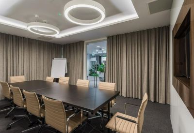 Professional meeting room with a large dark wood table, tan leather chairs, and grey privacy curtains.